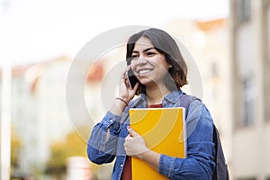 Happy Middle Eastern Student Female Talking On Cellphone While Walking Outdoors