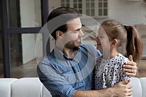 Happy millennial affectionate daddy hugging daughter girl with love