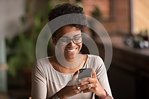 Happy millennial african american woman holding smartphone using ecommerce apps