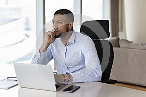 Happy millennial African freelance businessman looking away from office