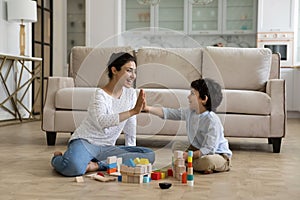 Happy millennial asian woman giving high five to kid son.