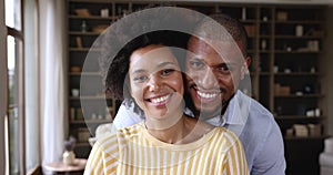 Happy millennial Black husband wife smiling looking at camera indoors