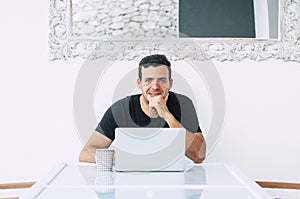 Happy millennial business young man sit on his desk with modern technology computer laptop smiling at the camera - minimalism.