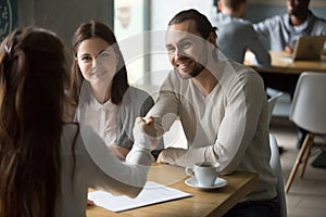 Happy millennial couple handshaking trusted broker after signing