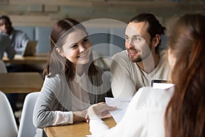 Happy millennial couple planning to sign mortgage contract at me