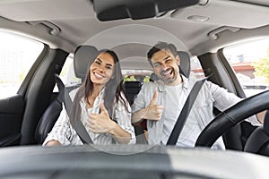 Happy millennial couple showing high five, sitting in car