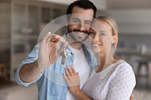 Happy millennial couple showing key from new house