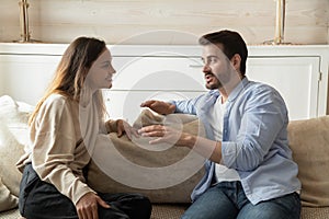 Happy millennial couple talk relaxing in living room