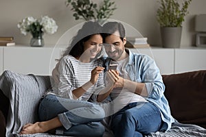 Happy millennial couple using online app on mobile phone together