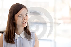 Happy millennial female employee look in distance dreaming photo