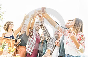 Happy millennial friends cheering with  wine at barbecue picnic outdoor - Adult people having fun drinking wine in vineyard at