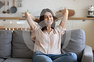 Happy millennial girl relax on comfortable sofa at home