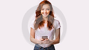 Happy Millennial Girl Using Smartphone Standing Over White Studio Background