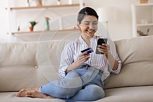 Happy Indian woman shop on cellphone with credit card