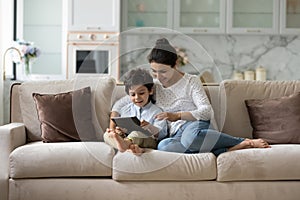 Happy millennial Indian mom gen Z son boy reading book