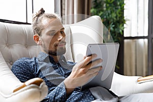 Happy millennial man using digital touchpad gadget.
