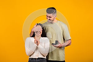 Happy millennial tall arab guy close eyes to amazed woman, hold box with ring