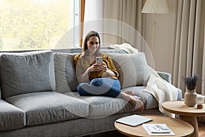 Happy millennial woman relaxing on couch at home