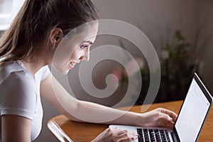 Happy millennial woman working on computer at home