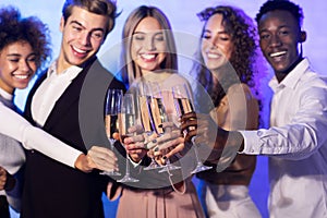 Happy millennials clinking champagne glasses having party standing indoor