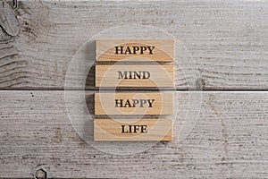 Happy mind happy life sign written on a stack of wooden pegs