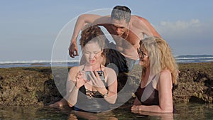 Happy mix family on vacation looking through pictures on phone of their holiday moments together as they are chilling