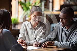 Happy mixed ethnicity couple customers sign mortgage loan contract