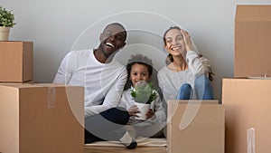 Happy mixed ethnicity family looking at camera sit with boxes