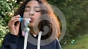 Happy mixed race African American girl teenager or young woman laughing, smiling and blowing bubbles at sunset or sunrise