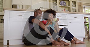 Happy mixed race couple drinking coffee in their kitchen