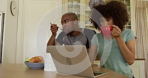 Happy mixed race couple eating breakfast in their kitchen