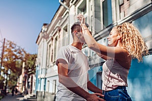 Mixed race couple in love listening to the music on phone and dancing on city street using earphones.