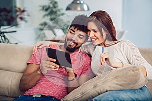 Happy mixed race couple shopping online at home, using credit card