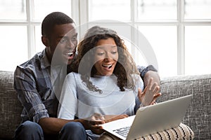 Happy mixed race couple surprised reading good news online