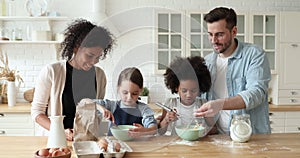 Happy mixed race cute kids helping young parents making dough