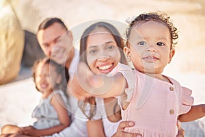 A happy mixed race family of four enjoying fresh air at the beach. Hispanic couple bonding with their daughters while