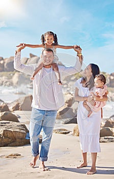 A happy mixed race family of four enjoying fresh air at the beach. Hispanic couple bonding with their daughters while