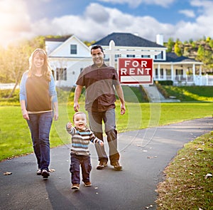 Happy Mixed Race Family in Front of Home and For Rent Sign