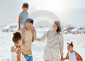 Happy mixed race family with three children laughing and talking while walking along the beach together. Loving parents