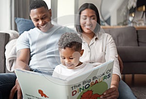 A happy mixed race family of three relaxing on the lounge floor and reading a story book at home. Loving black family