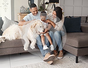 A happy mixed race family of three relaxing on the sofa with their dog. Loving black family being affectionate with a