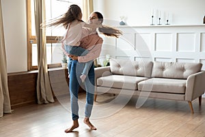 Happy mixed race mommy dancing to music with daughter.