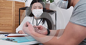 Happy mixed race pharmacy doctor woman in lab coat shows vaccine flask to male patient at light clinic office table.