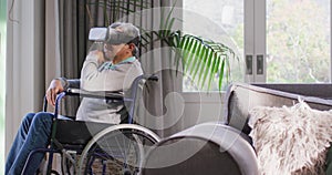 Happy mixed race senior man on wheelchair wearing vr headset and having fun at home