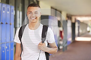 Happy mixed race teenage boy smiling in high school corridor