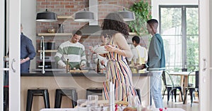 Happy mixed race woman holding bowl while cooking with group of friends