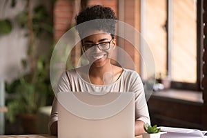 Happy mixed race woman student using laptop working studying indoor
