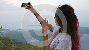 Happy Mixed Race Young Hipster Girl Taking Selfie on her Mobile Phone at Viewpoint. Phuket, Thailand. HD Slowmotion.