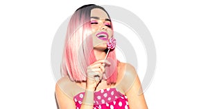 Happy model girl eating lollipop. Beauty Glamour young woman with trendy pink hair style and beautiful makeup