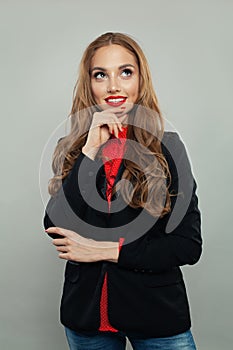 Happy model thinking and looking up on white background. Young businesswoman or student in black suit portrait
